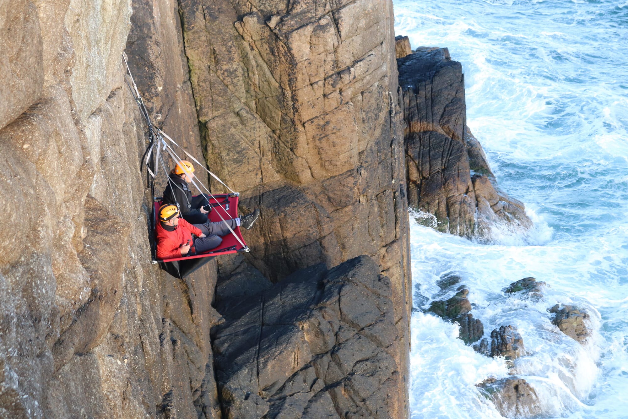 2 men resting on the side of a cliff in Wales