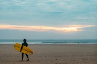 Best Surfing Beaches in Wales - A surfer with his board on a beach in Wales