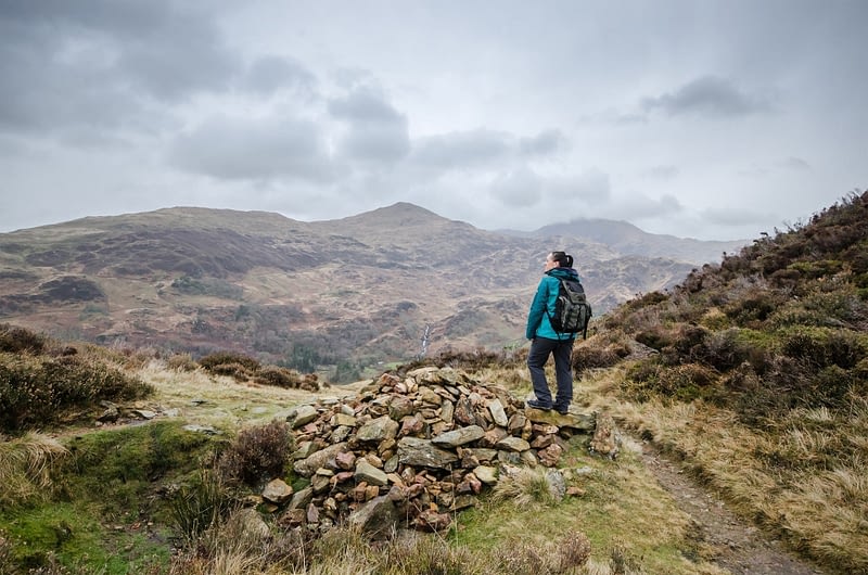 Female hiker with waterproof coat and backpack enjoying the view from the top of a hill in the Snowdonia National Park, Wales, UK
