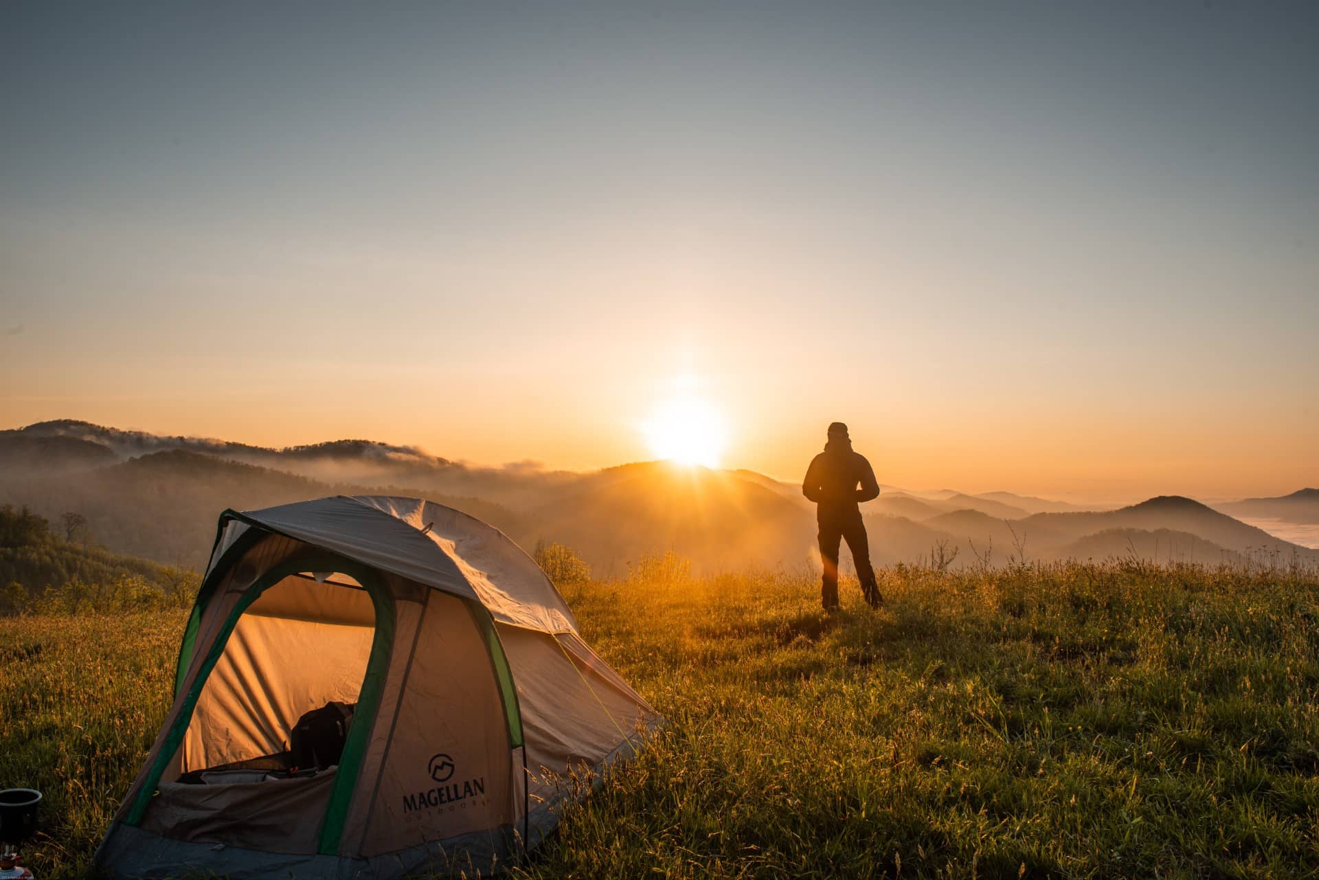 man camping enjoying the view at sunset