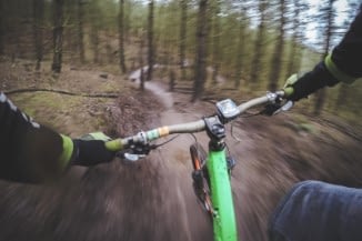 handle bar view of a cyclist on a wooded trail