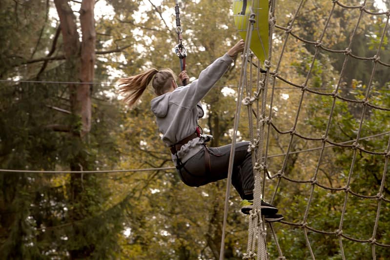 Woman using climbing ropes in the Forest of Dean