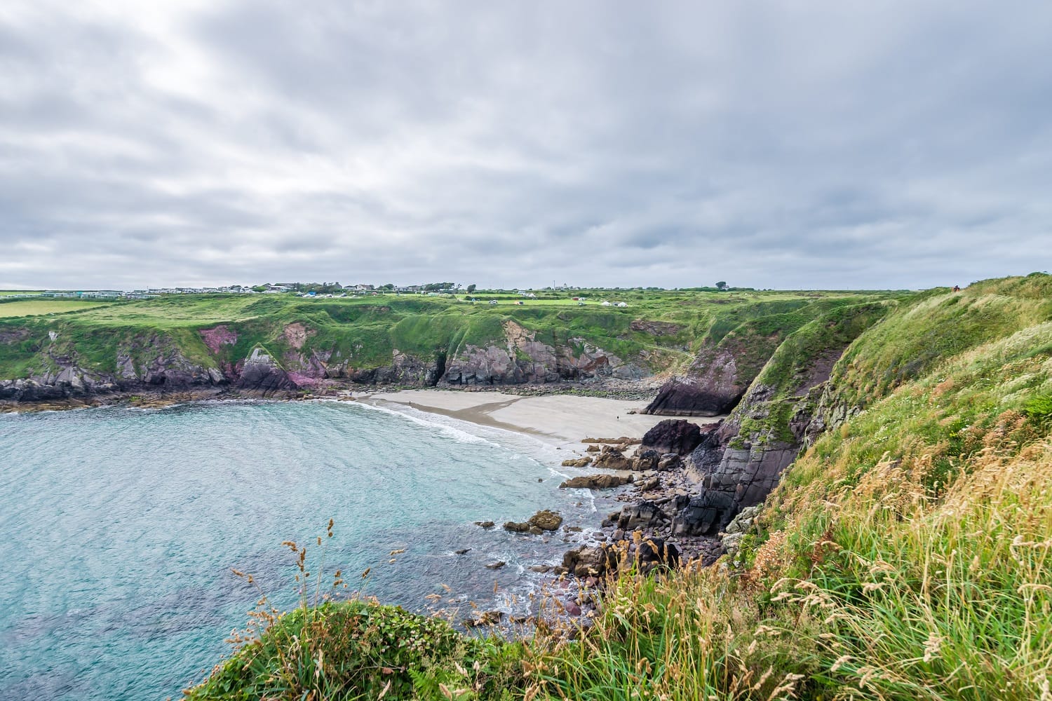 view of Caerfai Beach in St David's, Wales with an overcast sky
